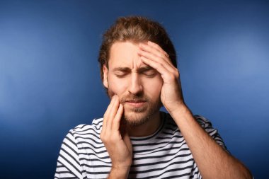 Arka planda baş ağrısı çeken genç bir adam