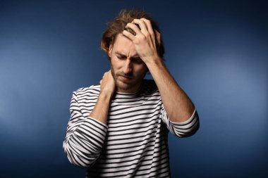 Arka planda baş ağrısı çeken genç bir adam