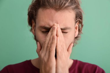 Arka planda baş ağrısı çeken genç bir adam