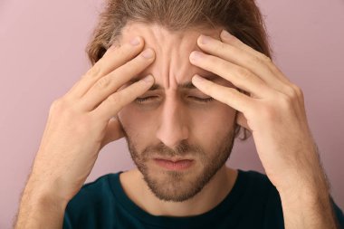 Arka planda baş ağrısı çeken genç bir adam
