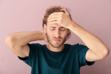 Arka planda baş ağrısı çeken genç bir adam