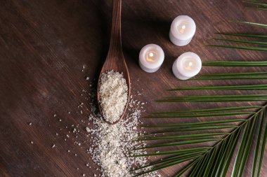 Güzel spa kompozisyon ile yanan mumlar, deniz tuzu ve palmiye yaprağı ahşap masa