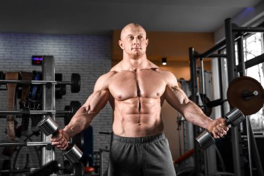 kaslı adam spor salonunda dumbbells ile eğitim
