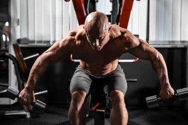 kaslı adam spor salonunda dumbbells ile eğitim