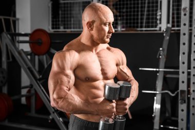 kaslı adam spor salonunda dumbbells ile eğitim