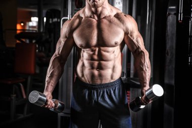 kaslı adam spor salonunda dumbbells ile eğitim