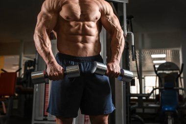 kaslı adam spor salonunda dumbbells ile eğitim