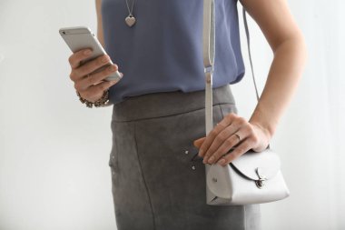 Güzel bir kadınla şık aksesuarlar ve açık renkli üstünde hareket eden telefon