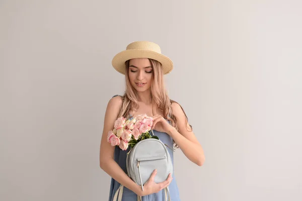 Schöne Junge Frau Mit Blumenstrauß Und Rucksack Auf Grauem Hintergrund — Stockfoto