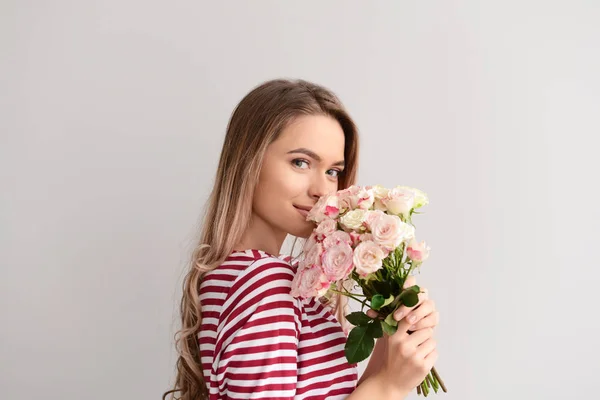 灰色の背景の上に花の花束と美しい若い女性 — ストック写真
