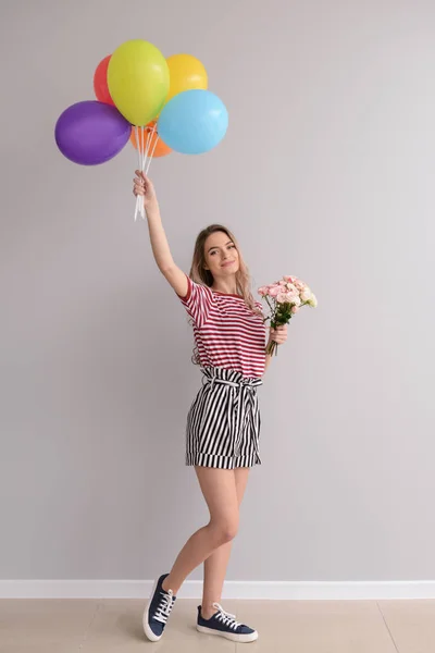 Mulher Bonita Com Buquê Flores Balões Brilhantes Perto Parede Cinza — Fotografia de Stock