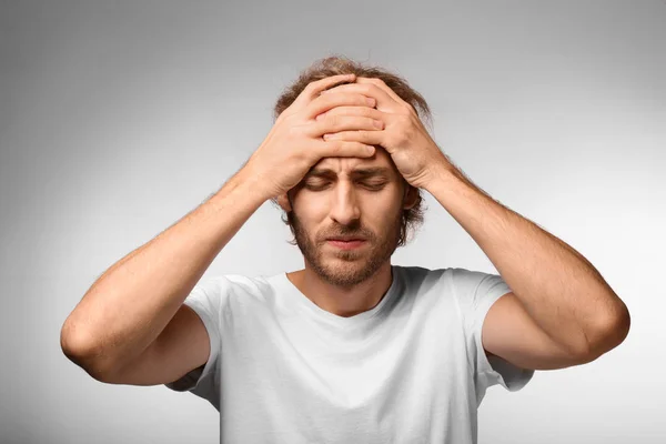 Young Man Suffering Headache Light Background — Stock Photo, Image