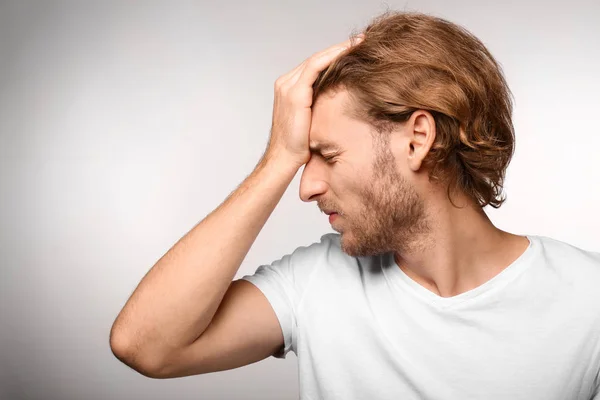 Young Man Suffering Headache Light Background — Stock Photo, Image