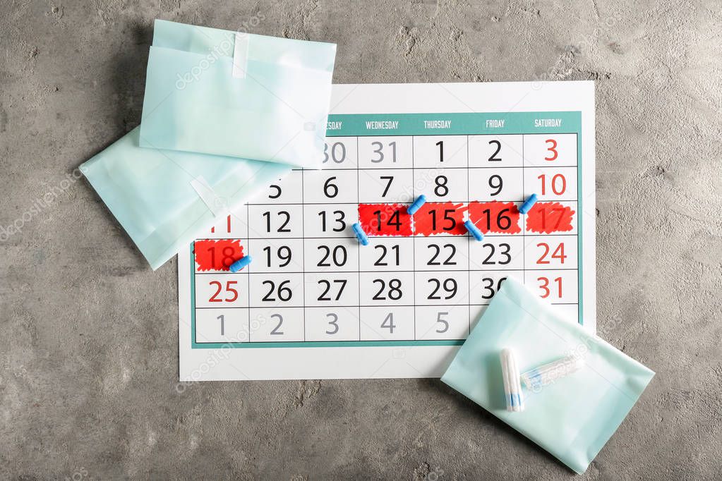 Menstrual calendar with feminine products and pills on grey background