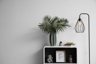 Işık duvarının yakınında tablo vazo ile yeşil tropikal yaprak