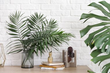 Işık duvarının yakınında tablo vazo ile yeşil tropikal yaprak