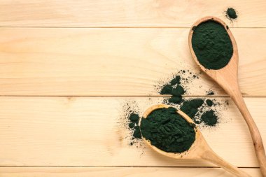 Spirulina tozu ahşap masa üzerinde kaşıklarla