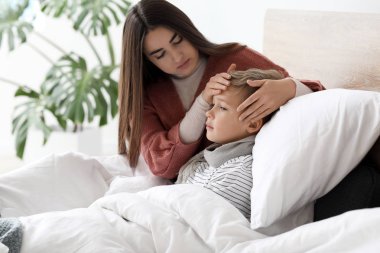 Anne, oğluna evde hasta bir şekilde bakıyor.