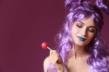 Güzel genç ve kadın ile olağandışı makyaj renk arka plan üzerinde tatlı lolipop