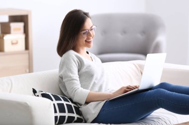 Evde dizüstü bilgisayarla çalışan genç bir kadın.