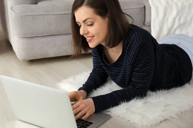 Evde dizüstü bilgisayarla çalışan genç bir kadın.