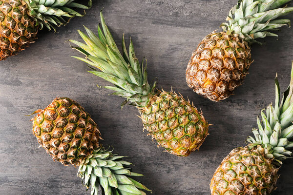 Ripe pineapples on grey wooden background