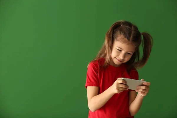 色の背景にスマート フォンで遊ぶかわいい女の子 — ストック写真