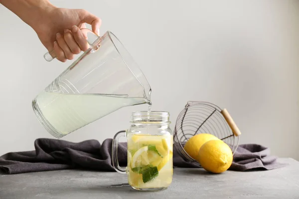 Mulher Derramando Limonada Fresca Frasco Pedreiro Mesa — Fotografia de Stock