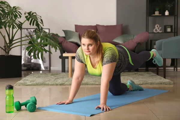 Beautiful plus size girl training at home. Concept of body positivity