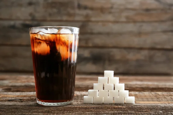 Glass of soda and sugar on wooden table