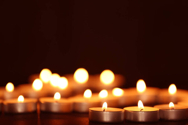 Beautiful burning candles on table against dark background