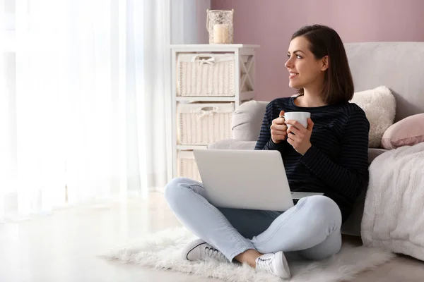 手提电脑的年轻妇女在家喝咖啡 — 图库照片