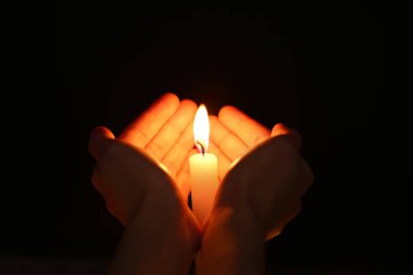 Karanlıkta mum yanan ile eller