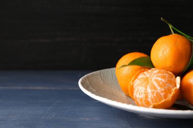 Ahşap masa üzerinde lezzetli lezzetli sulu mandalina ile plaka
