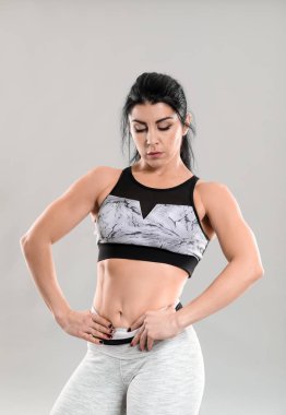 Gri arka plan üzerinde sportif kaslı kadın