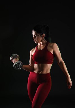 Koyu arka plan üzerinde halter ile sportif kaslı kadın