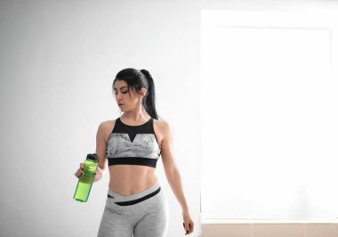 Şişe su içinde jimnastik salonu ile sportif kaslı kadın