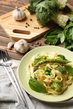 Lezzetli makarna ve ahşap masa üzerinde yeşil sebzeler ile plaka