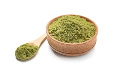 Beyaz arka planda pudralanmış kibrit çayı ile kase ve kaşık.