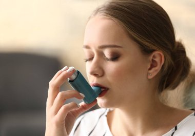 Young woman with inhaler having asthma attack at home clipart
