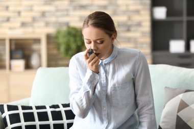 Astım spreyi olan genç bir kadın evde astım krizi geçiriyor.