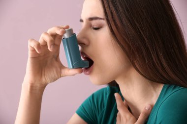 Astım spreyi olan genç bir kadın renk geçmişinde astım krizi geçiriyor.
