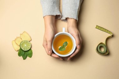Renk arka plan üzerinde kilo kaybı çay ile eller