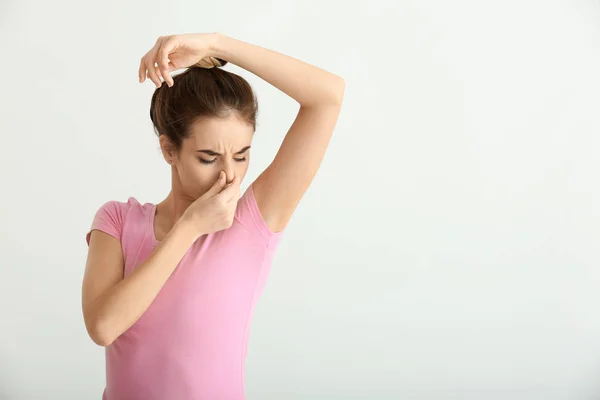 美丽的年轻女子在轻的背景感觉汗味 使用除臭剂的概念 — 图库照片