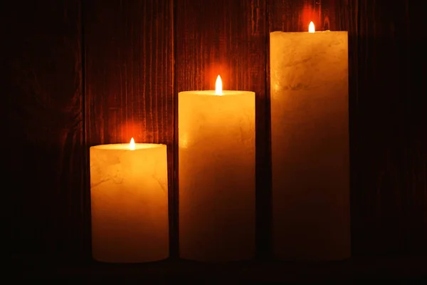 Beautiful burning candles on dark wooden background