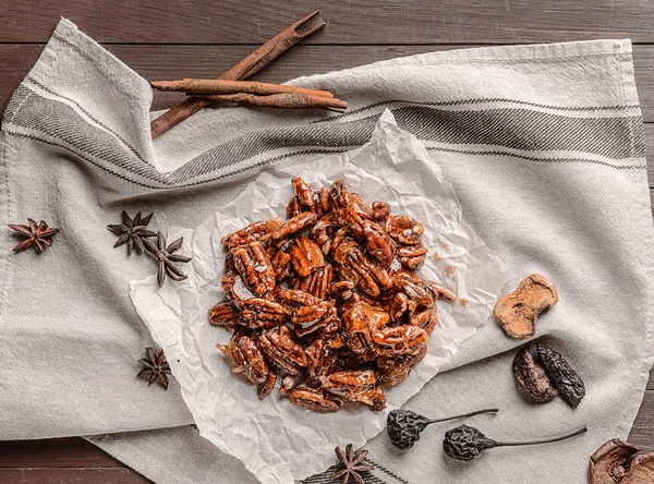 Tasty candied pecan nuts on wooden table