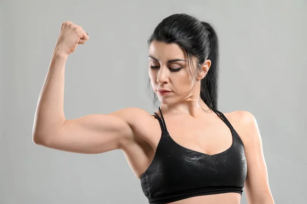 Sporty muscular woman on grey background