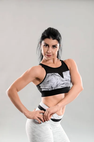 Sporty muscular woman on grey background