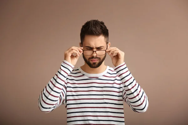 Portrait of man with bad sight on color background