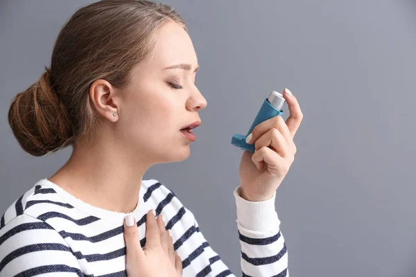 Junge Frau Mit Inhalator Hat Asthmaanfall Vor Grauem Hintergrund — Stockfoto